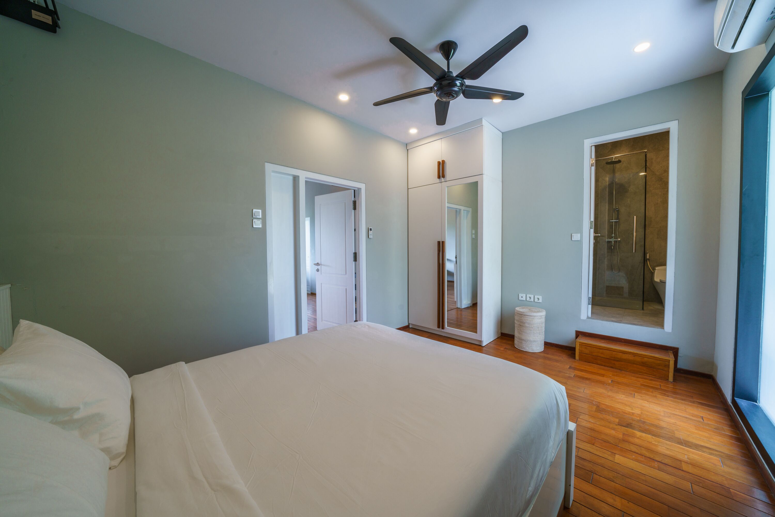Quarto com cama grande, ventilador de teto, closet espaçoso, chuveiro e janela.