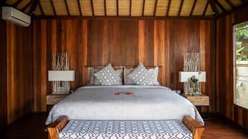 Un dormitorio con paneles de madera, una cama, dos mesitas de noche y un banco.