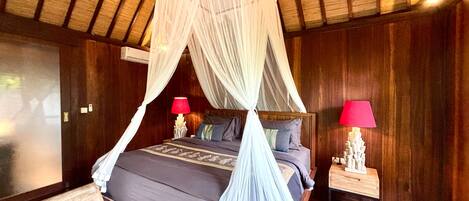 A four-poster bed with a canopy, two bedside tables with lamps, and wooden paneling on the walls.