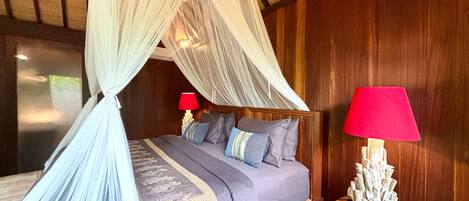Una cama con dosel, dos lámparas de noche y una mesita de noche de madera decorativa.
