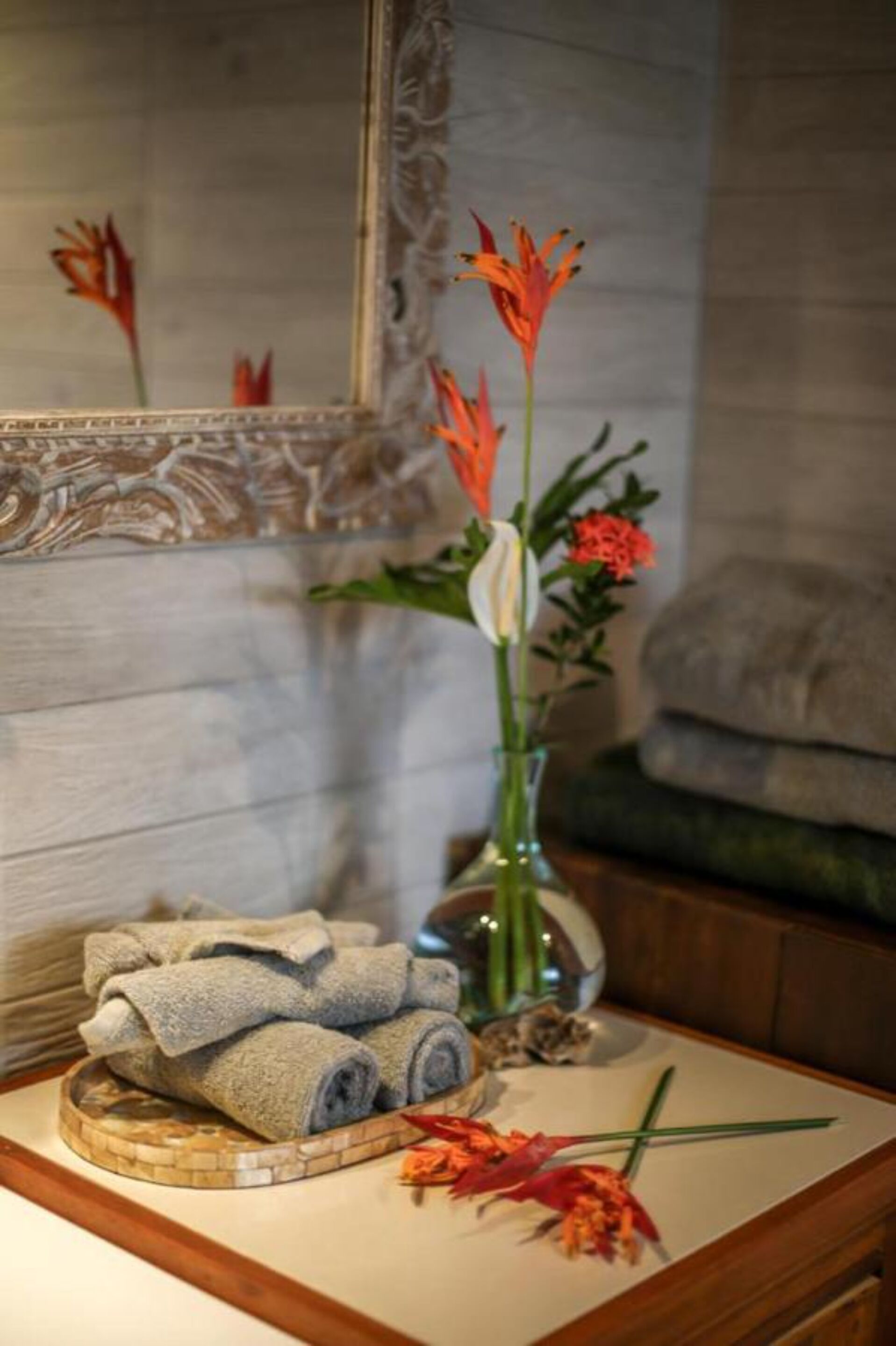 A bathroom vanity with a towel rack, a vase with flowers, and a mirror.