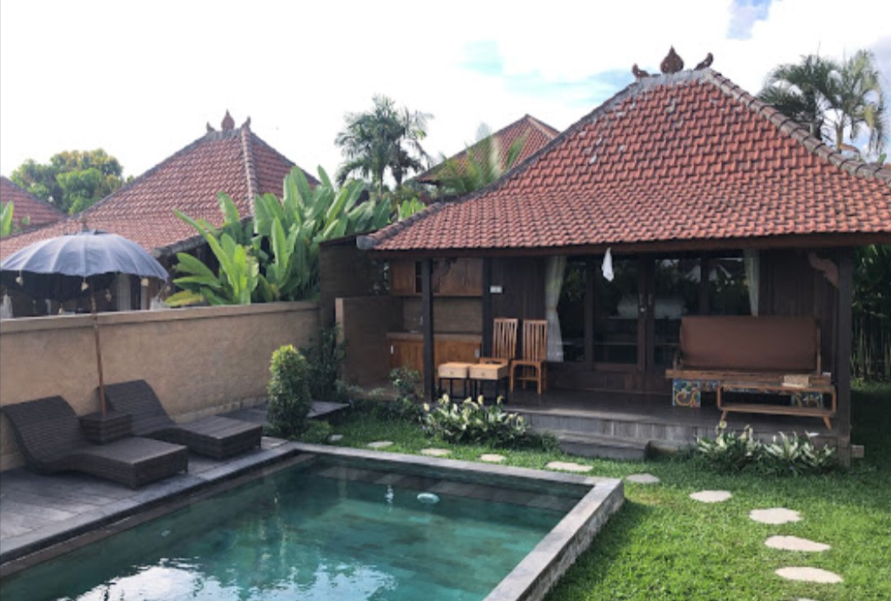 A poolside area with a tiled roof, lounge chairs, and a small seating area with a table and chairs.