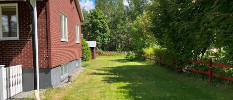 A red brick house with a white fence and a grassy yard.