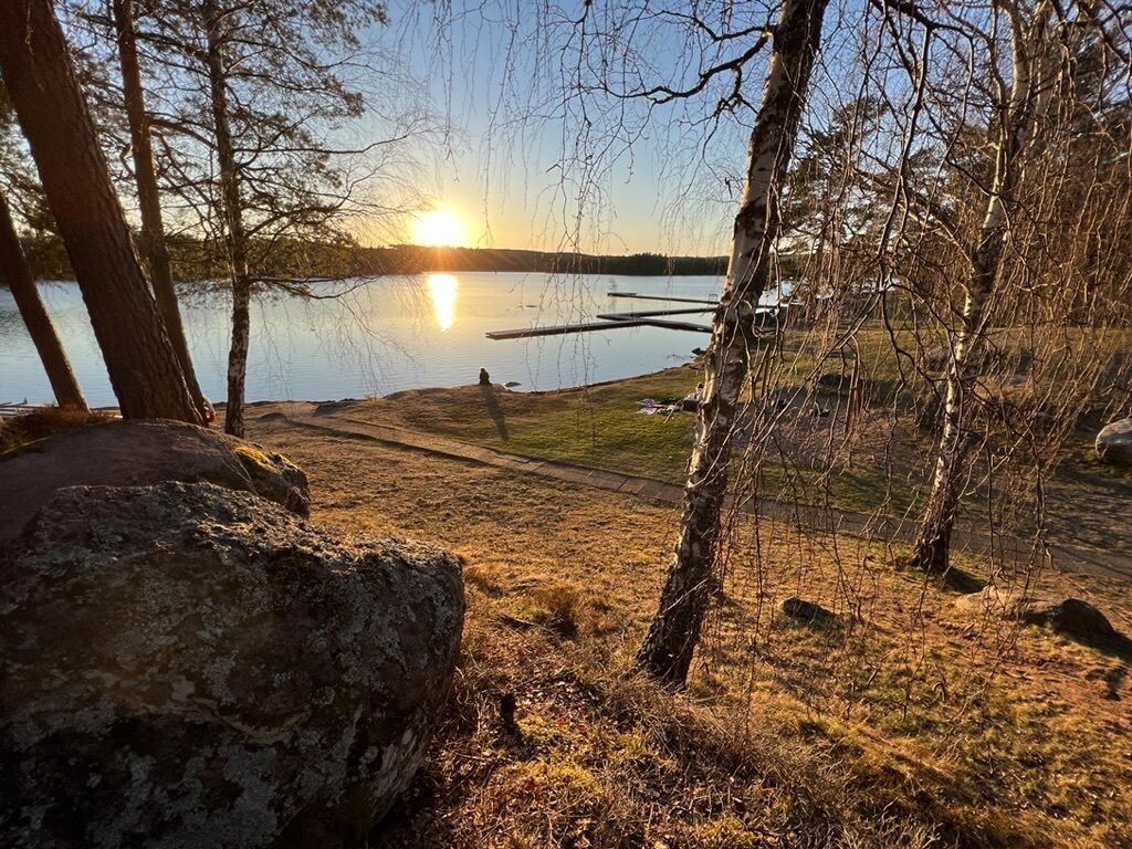 Vista para o lago com um pôr do sol, árvores e um píer.