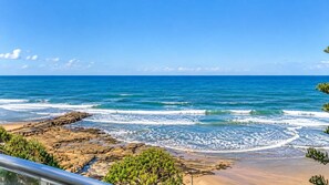 A coastal view with rocky terrain and a clear blue sky.