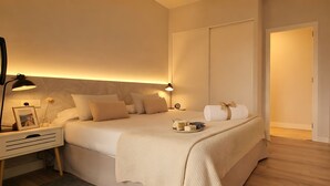 A hotel room with a bed, bedside table, lamp, and a tray with toiletries.