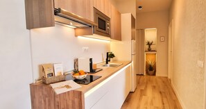 Een moderne keuken met een inbouwoven, magnetron en een strak aanrecht.