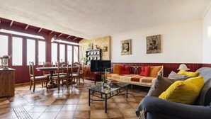 Un salon spacieux comprenant un coin repas, un ensemble de canapés et un téléviseur.
