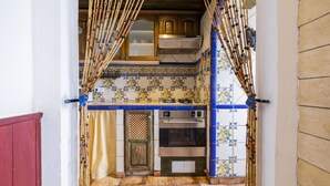 Une cuisine équipée d’une cuisinière, d’un four et d’une fenêtre ornée d’un rideau en bambou.