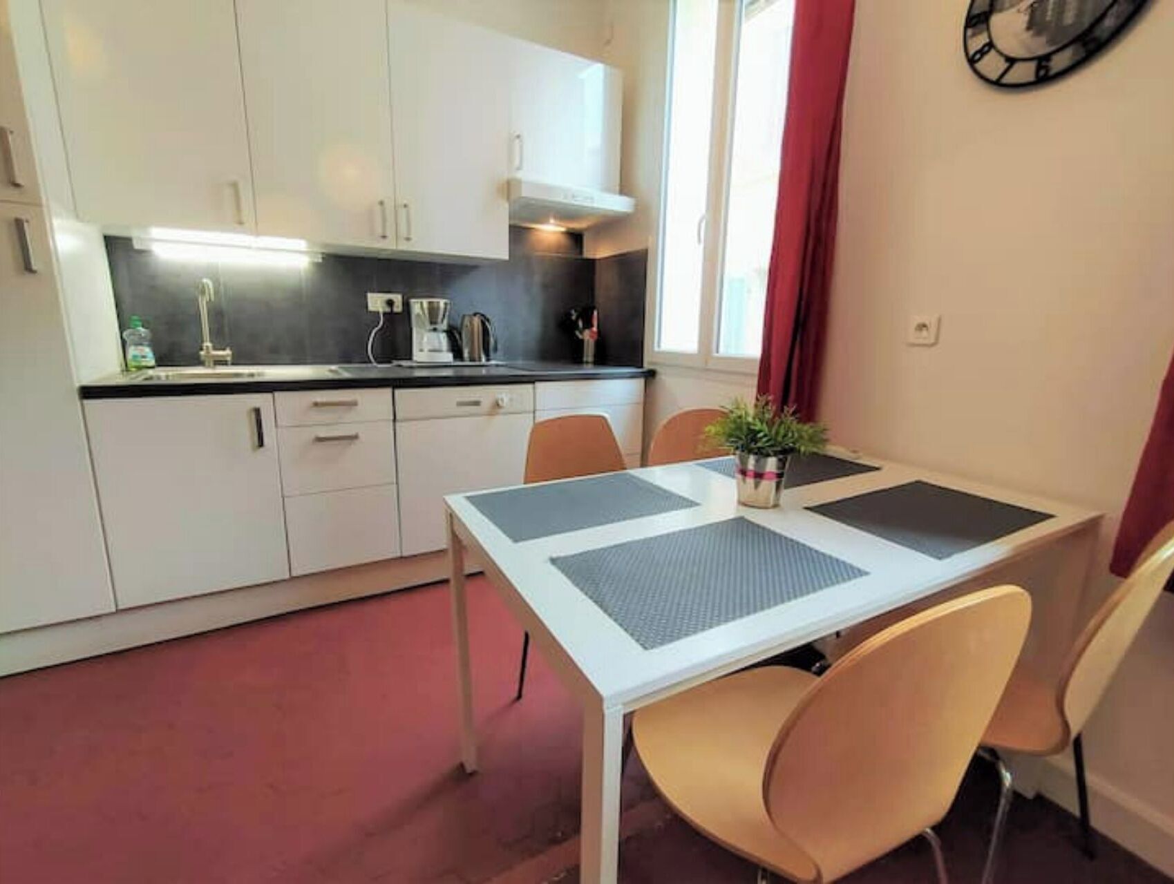 A compact kitchen with white cabinets, a black countertop, and a dining area with a table and chairs.