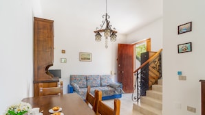 A dining area with a wooden table, chairs, and a sofa. There is a staircase with a railing leading to another room. - 3055 Villetta Sunset by Barbarhouse (Gallipoli)