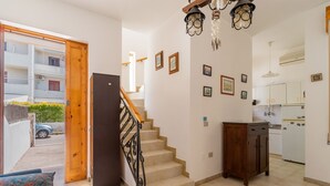 A staircase leading to a second floor, a kitchen area with white cabinets, and a dining area with a table and chairs. - 3055 Villetta Sunset by Barbarhouse (Gallipoli)