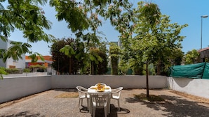 An outdoor dining area with a white table and chairs, surrounded by trees and a white wall. - 3055 Villetta Sunset by Barbarhouse (Gallipoli)