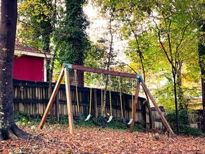 Guests can enjoy a backyard swing set with four swings and a wooden frame.