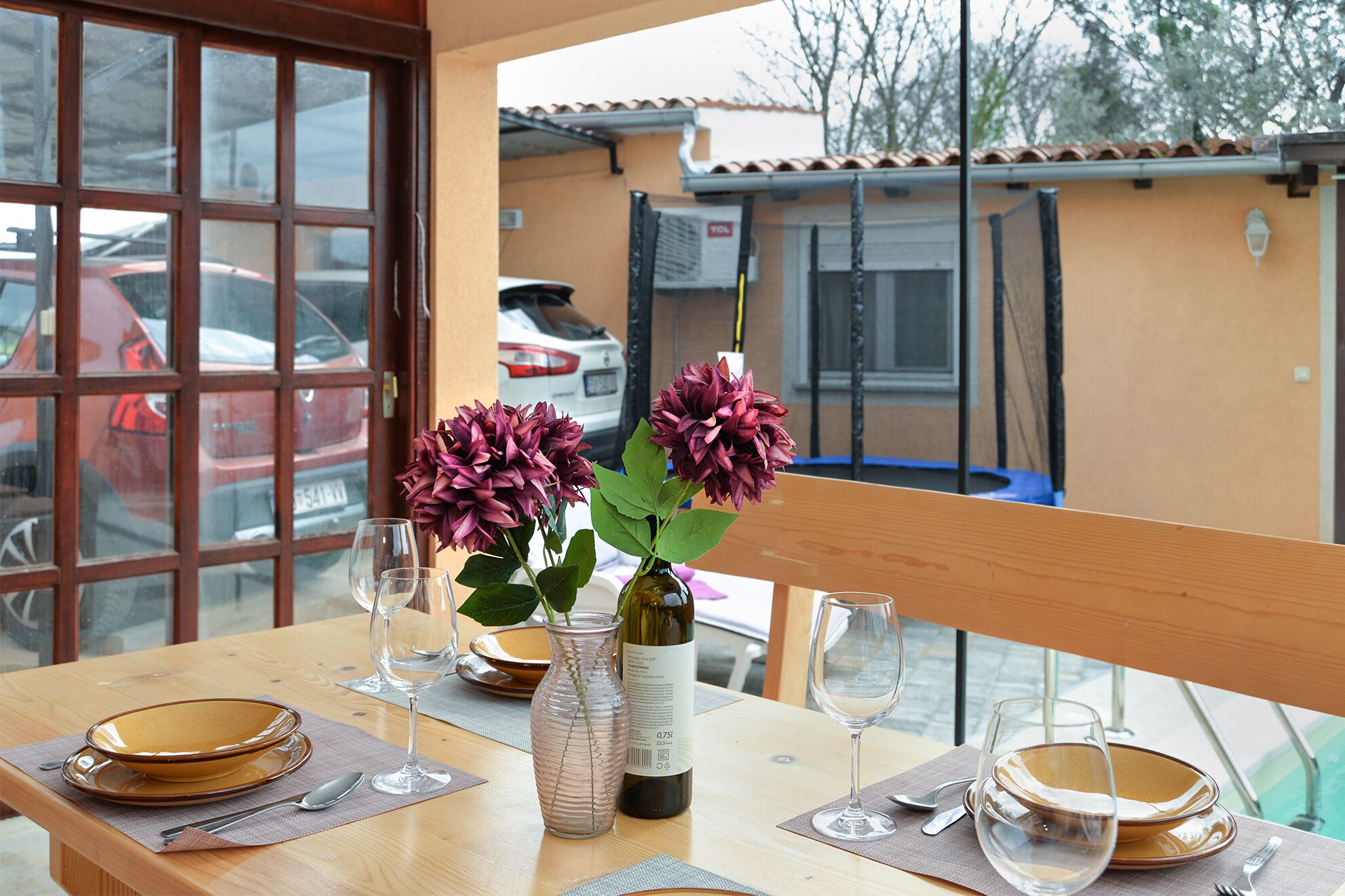 A dining table with plates, glasses, and a bottle of wine.