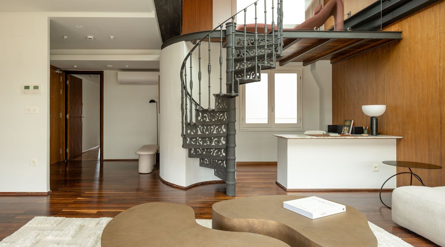 Un interno moderno con una scala a chiocciola, un banco reception bianco e un'accogliente area relax.