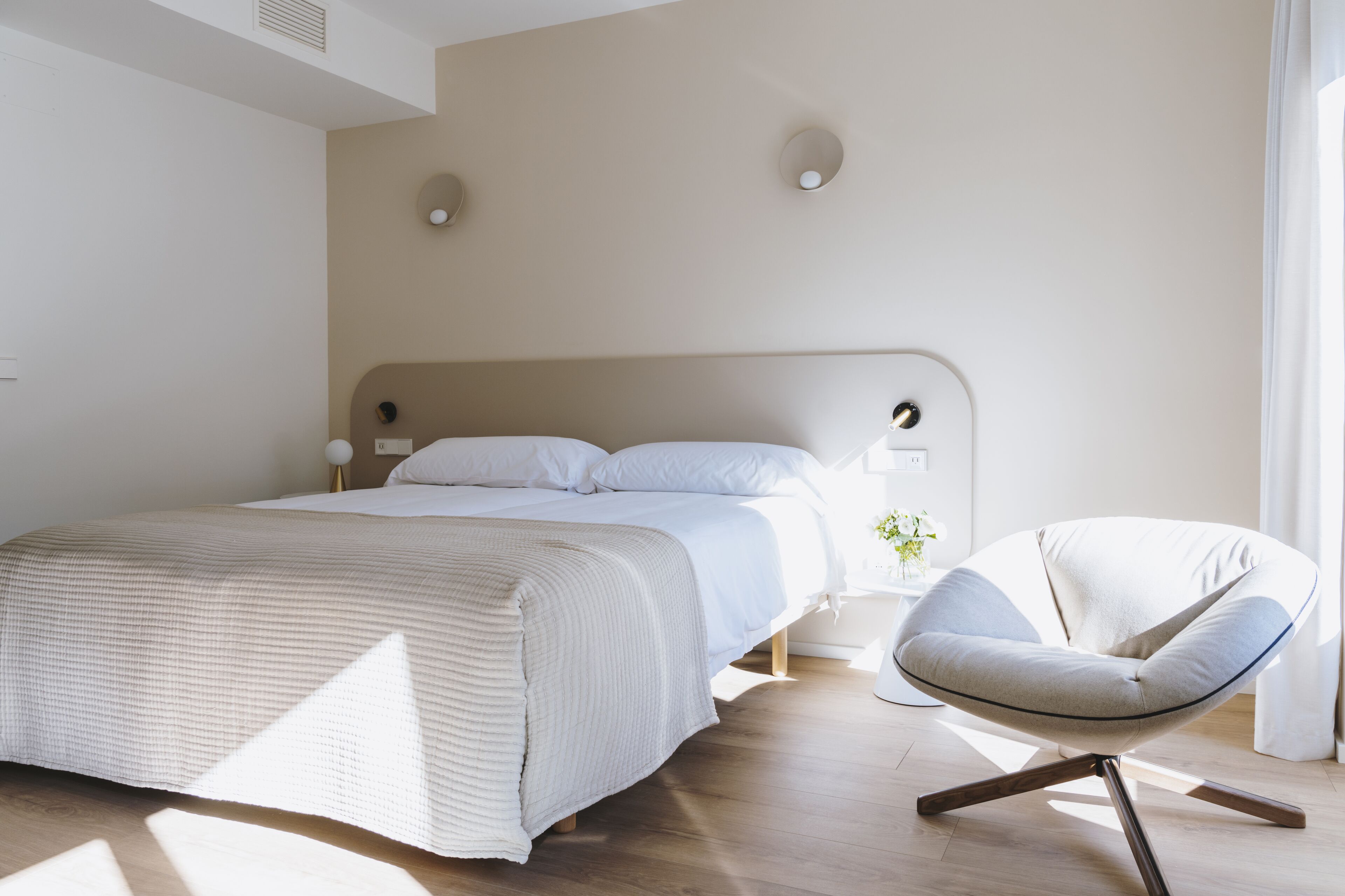 Un dormitorio moderno con una cama grande, una silla y una mesita de noche.