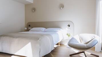 Un dormitorio moderno con una cama grande, una silla y una mesita de noche.