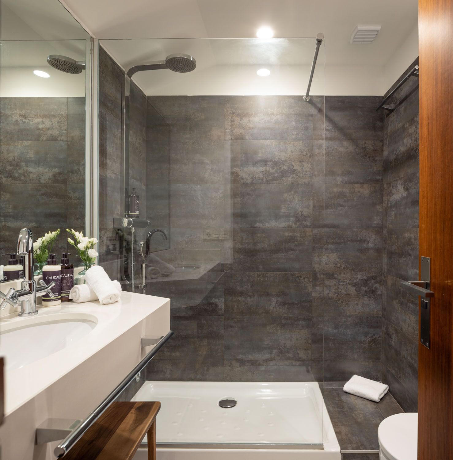 Un baño moderno con cabina de ducha de vidrio, bañera y tocador con espejo.