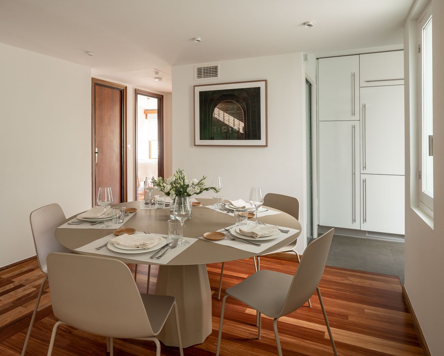 Een eetgedeelte met een ronde tafel voor vier personen, omringd door moderne stoelen.