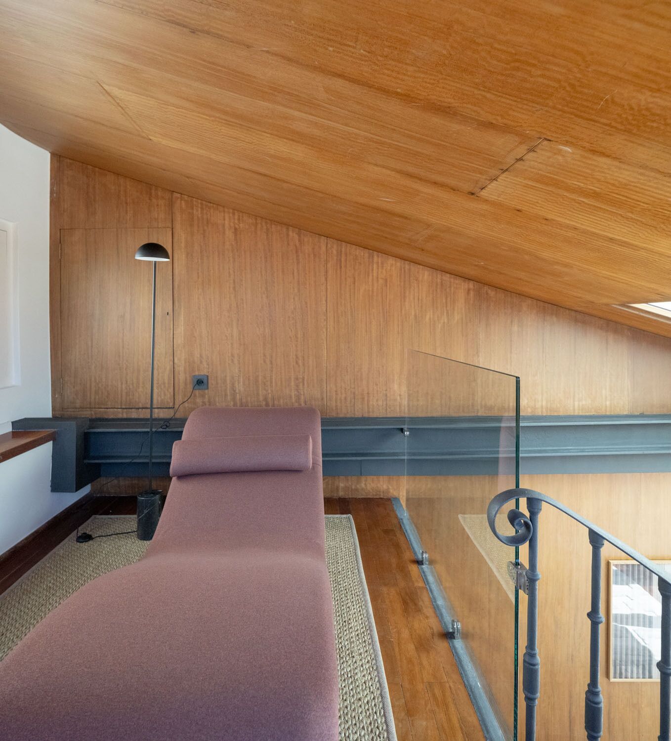 A room with a wooden ceiling, a massage table, a glass railing, and a view of the outside.