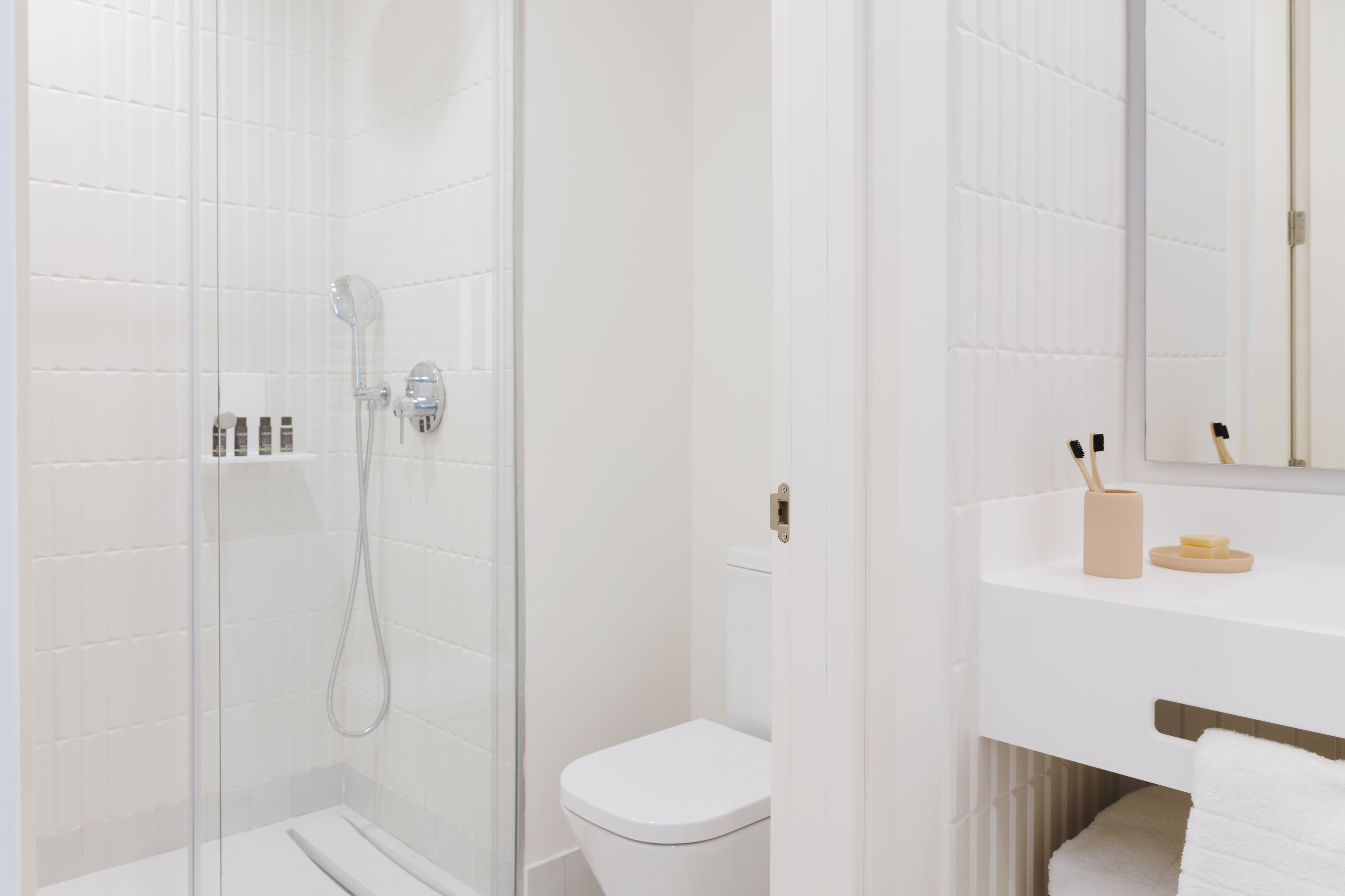 A modern bathroom with a glass-enclosed shower, a white toilet, and a vanity with a mirror.