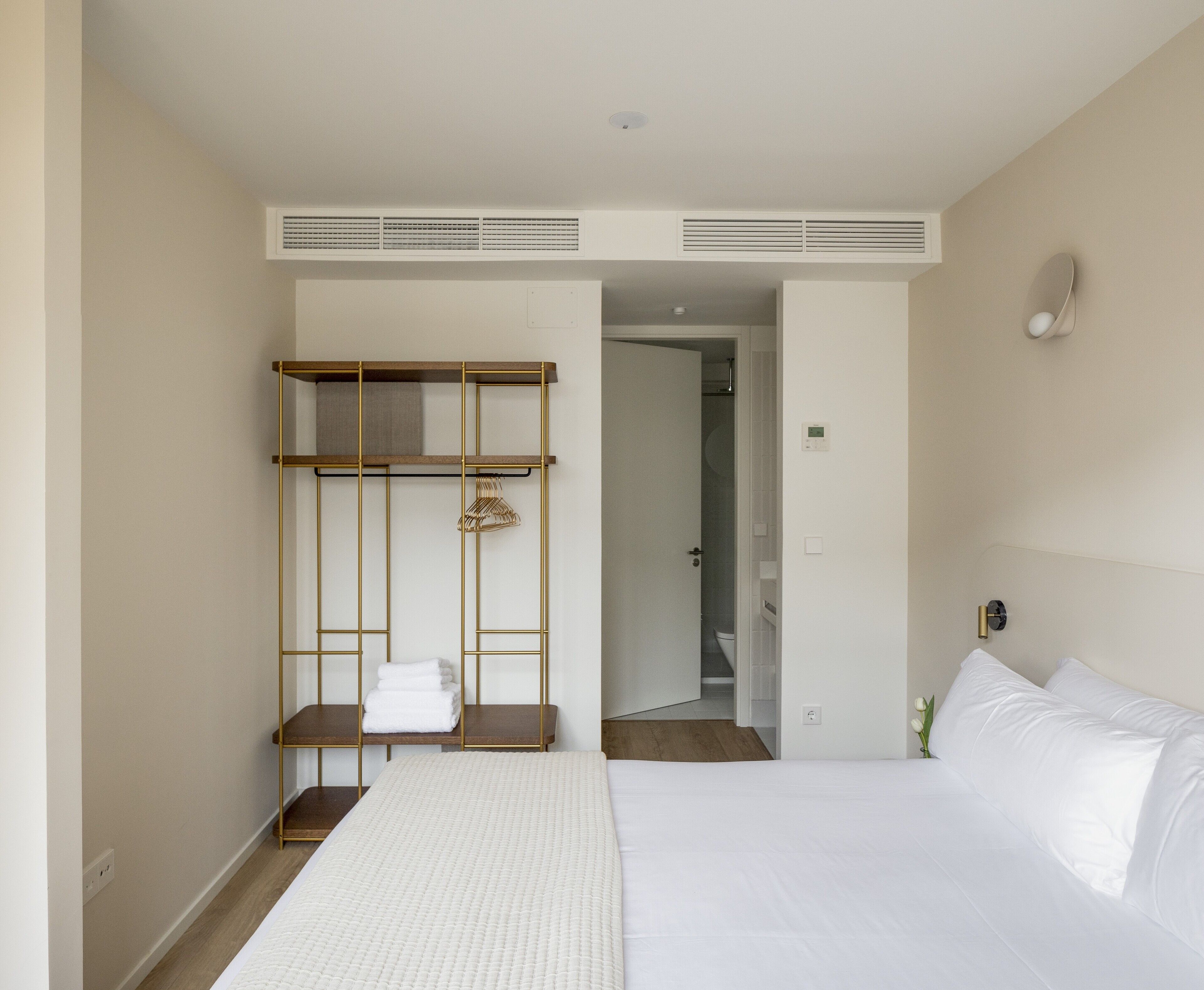Habitación de hotel con cama, armario de madera, toallero y puerta de baño.