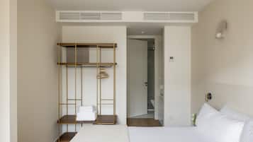 Habitación de hotel con cama, armario de madera, toallero y puerta de baño.