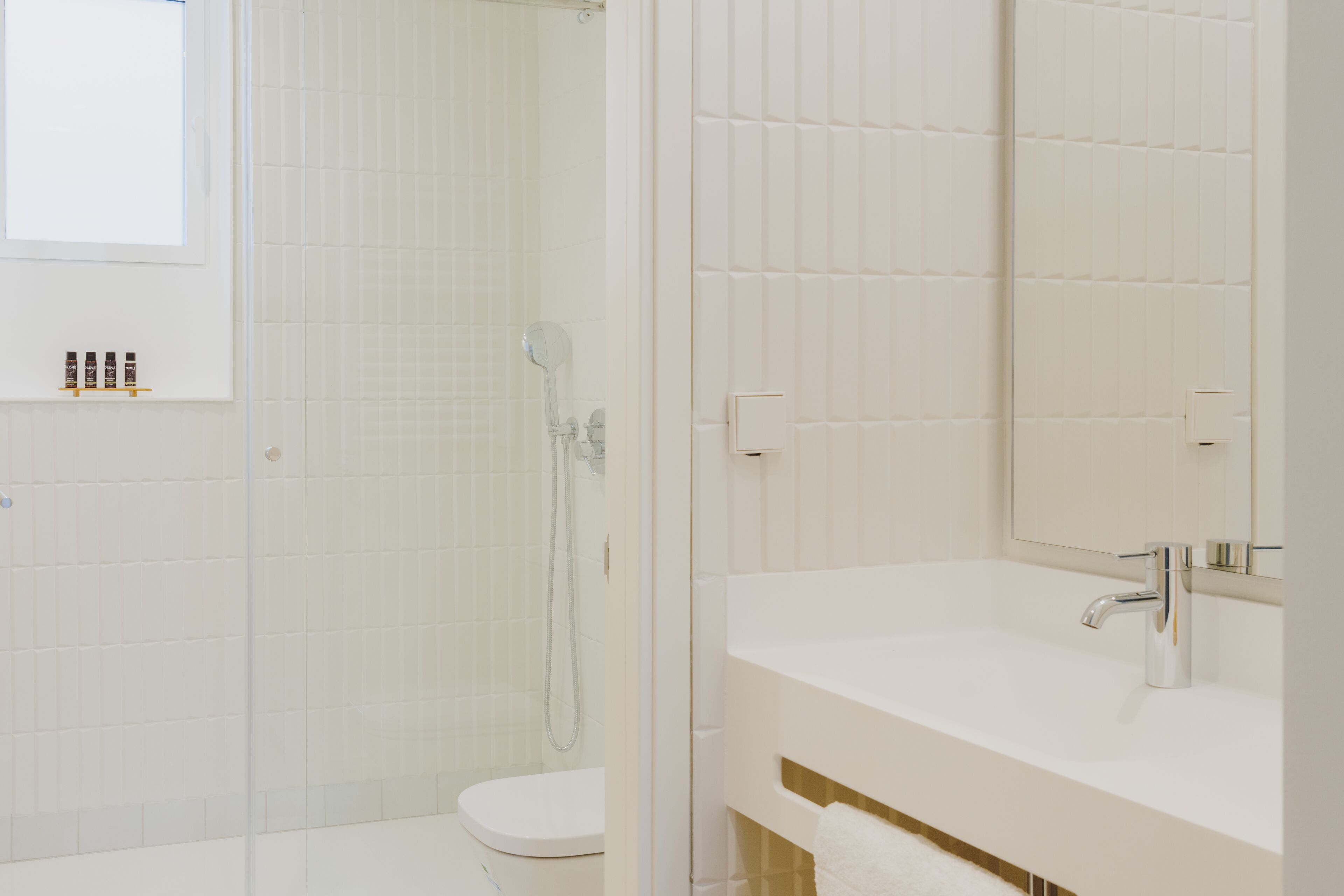 A modern bathroom with a glass-enclosed shower, a white toilet, and a vanity with a mirror.