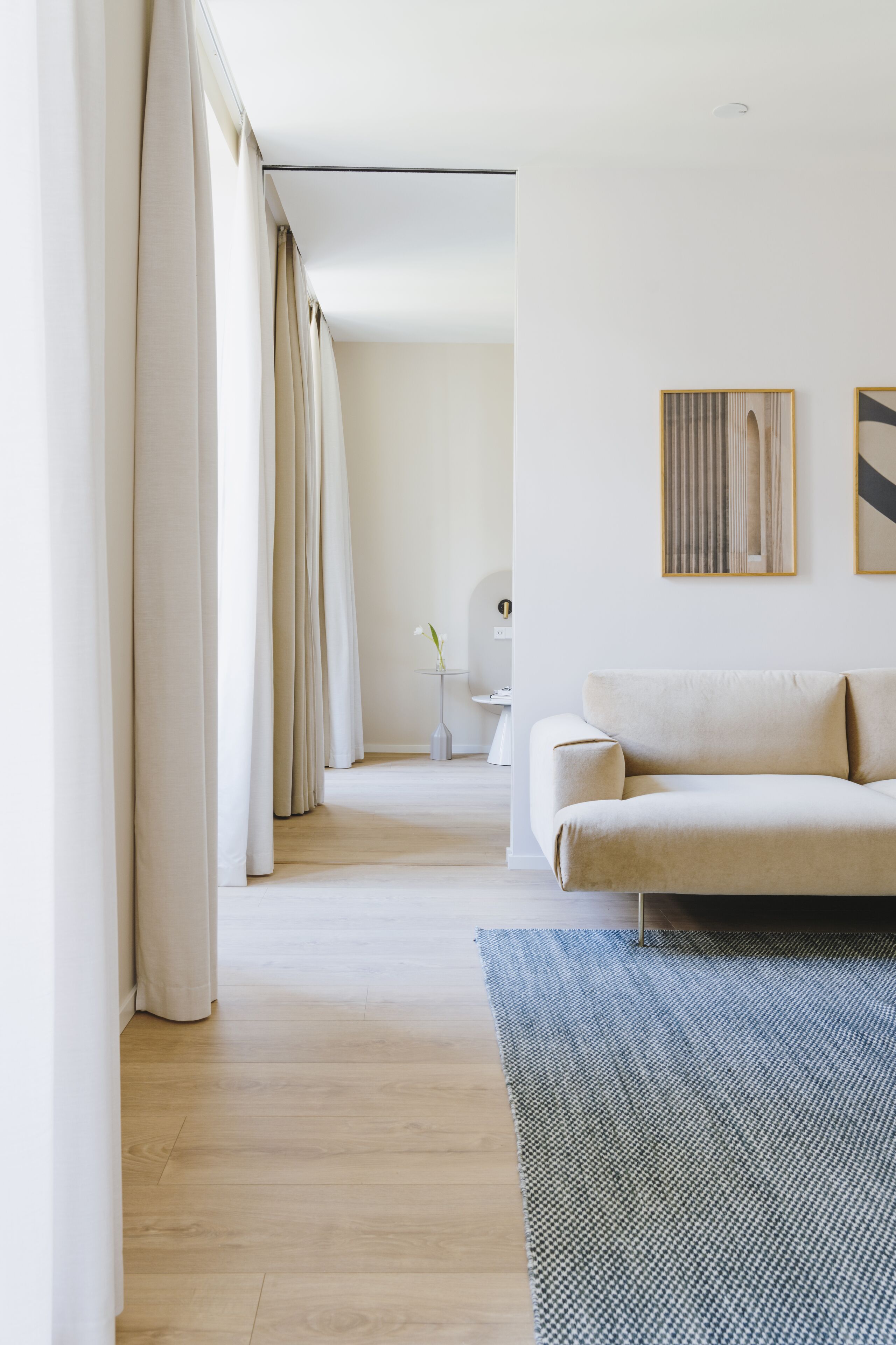 A modern living room with a sofa, a patterned rug, and a minimalist decor.