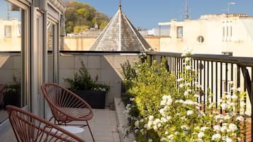 Un balcon avec deux fauteuils en osier, une plante en pot et une jardinière ornée de fleurs blanches.