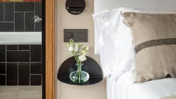 Un dormitorio con cama, mesita de noche con un florero y una lámpara fijada a la pared.