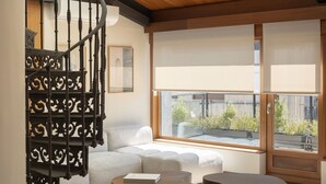 A modern living room with a spiral staircase, large windows, and a view of greenery outside. - The Passage Apartments (San Sebastián)