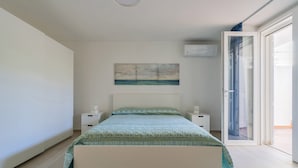 A bedroom with a bed, bedside tables, a painting, and a sliding glass door to a balcony. - 2824 Villino Anna by Barbarhouse (Racale)