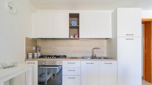 A compact kitchen with white cabinets, a built-in oven, and a sink. - 2824 Villino Anna by Barbarhouse (Racale)