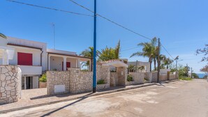 A residential street with stone walls and red shutters, clear skies, and palm trees. - 2824 Villino Anna by Barbarhouse (Racale)