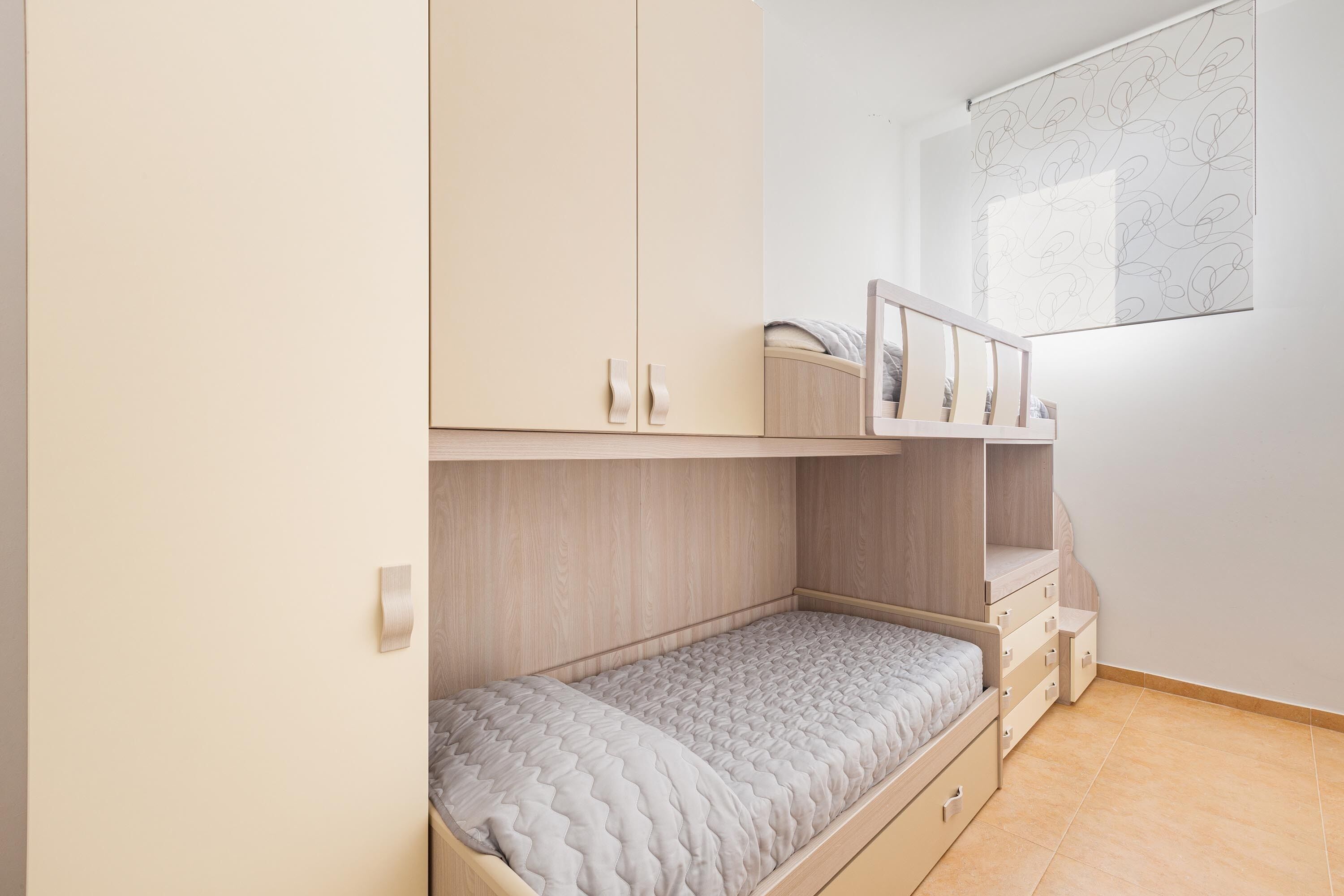 Et soveværelse med køjeseng, skrivebord og garderobe.