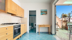 Une cuisine de taille réduite, dotée de meubles en bois, d’une cuisinière à gaz et d’un four encastré.