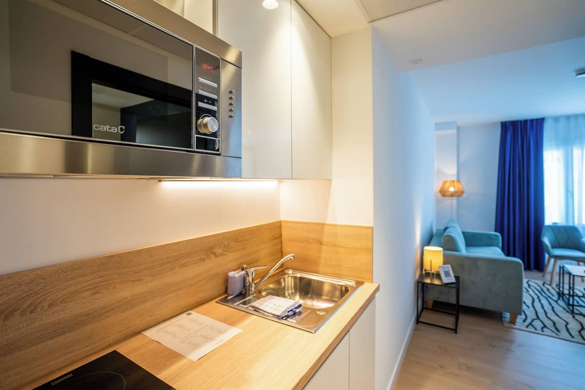 Een moderne keuken met een rvs magnetron, een spoelbak en een houten aanrecht.
