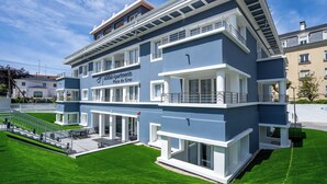 A modern multi-story building with a blue facade, a sign reading "Apartments Playa de Gros," and a well-maintained lawn. - abba Apartments Playa de Gros San Sebastián (San Sebastián)