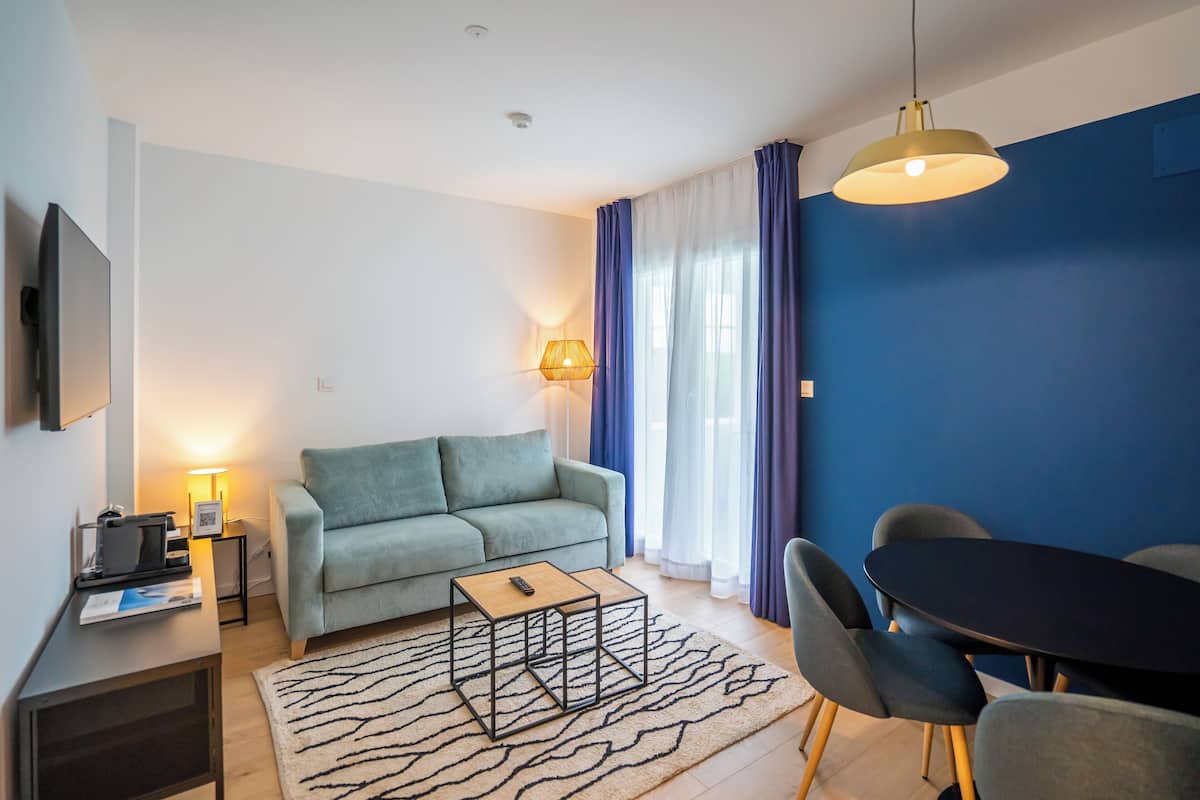 Een moderne woonkamer met een bank, een salontafel, een televisie en een eethoek met stoelen en een tafel.