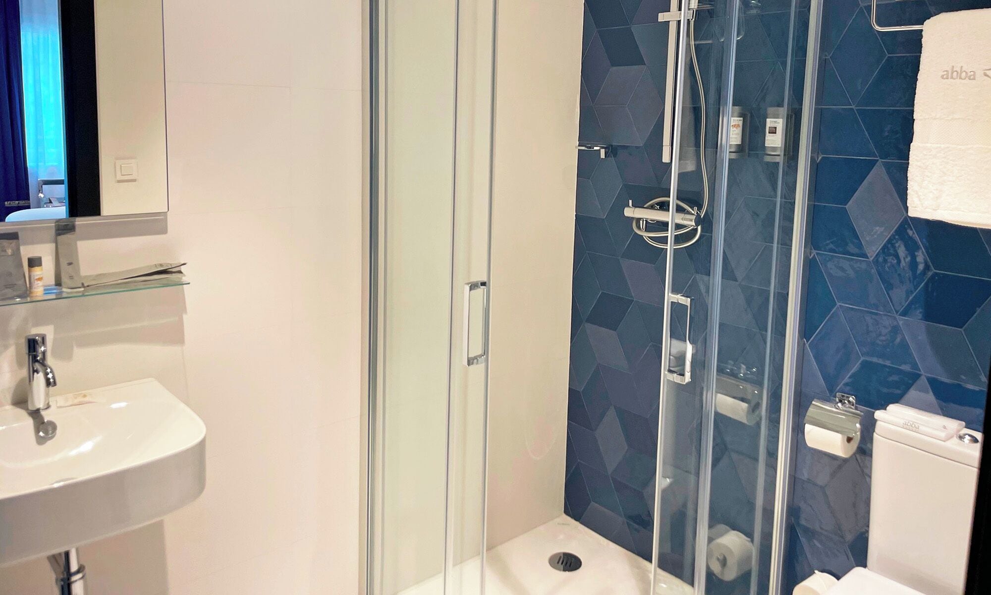 A modern bathroom with a glass-enclosed shower, a white sink, and a toilet.