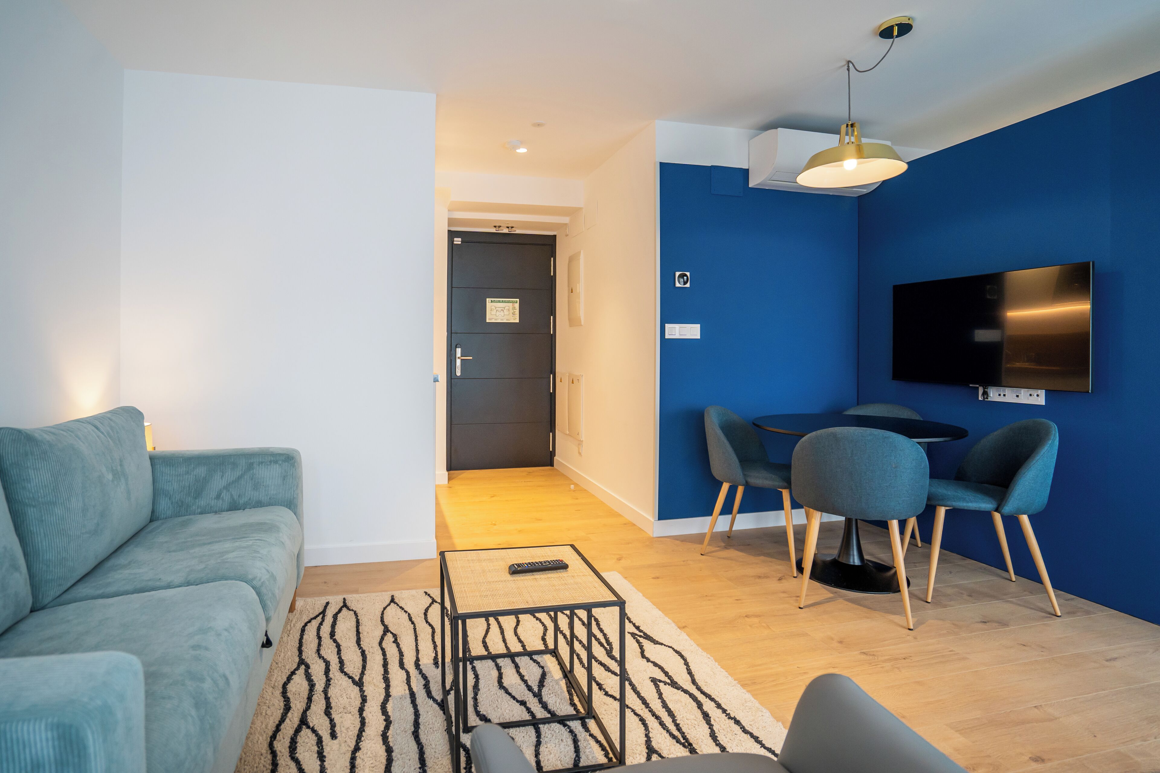 Een moderne woonkamer met een bank, een salontafel en een eethoek met stoelen en een televisie.