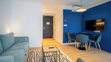 Een moderne woonkamer met een bank, een salontafel en een eethoek met stoelen en een televisie.
