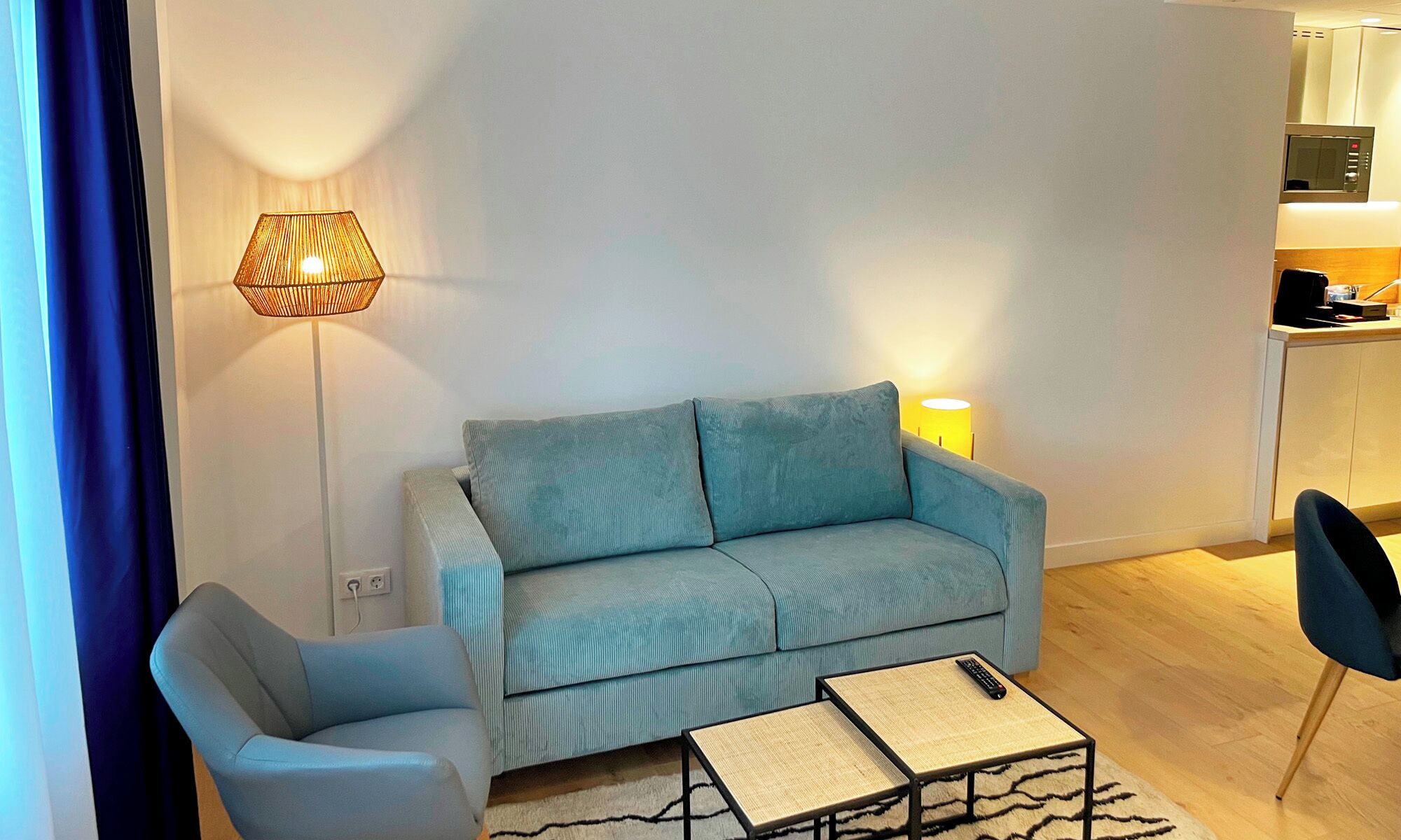 A modern living room with a sofa, a chair, a coffee table, and a lamp.