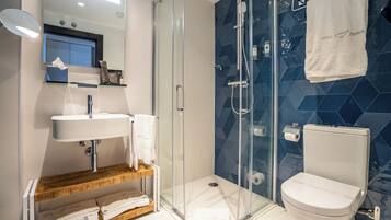 A modern bathroom with a glass-enclosed shower, a white sink, and a toilet.