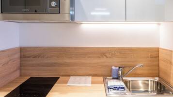 Una cocina moderna con microondas integrado, un lavamanos y una encimera de madera.
