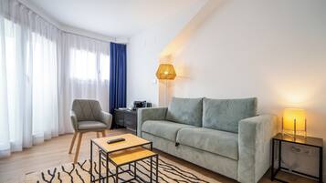 Una sala de estar moderna con sofá, sillón, mesa de centro, lámpara y alfombra.