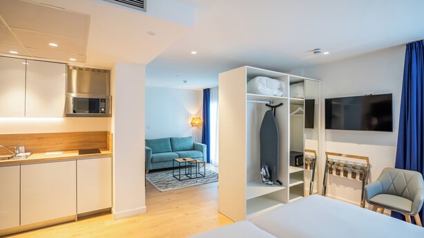 A modern hotel room with a kitchenette, a sofa, a TV, and a bed. - abba Apartments Playa de Gros San Sebastián (San Sebastián)