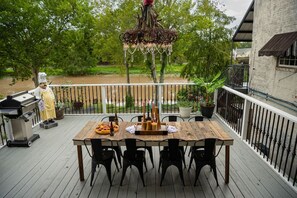 A wooden deck with a dining table and chairs, a grill, and a statue of a chef. - Side-By-Side Both Places, Groups Can Spend More Time Together! (New Iberia)